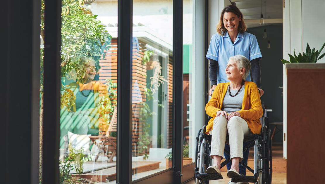 Health care worker walking with elderly woman.